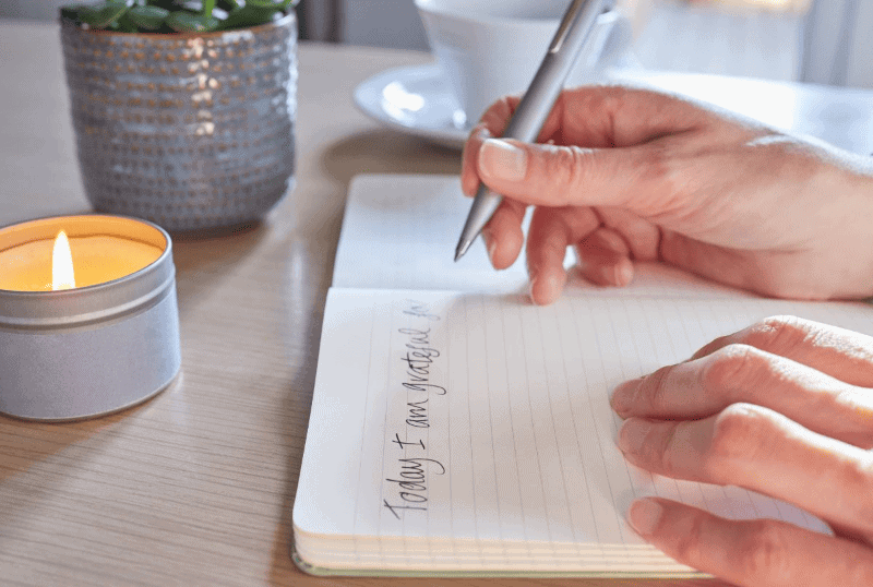 Woman's hand writing in healing journal