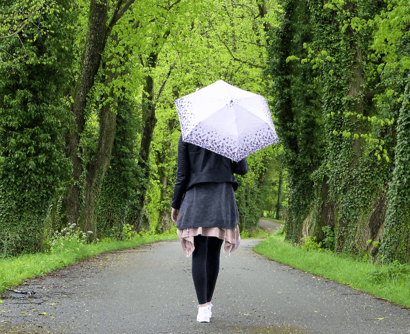 Woman walking in forest with umbrella