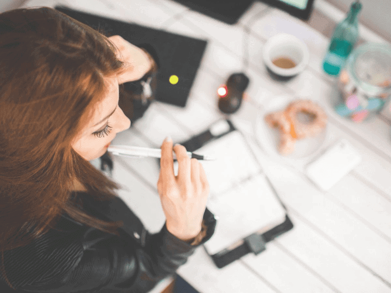 Woman thinking with pen in mouth