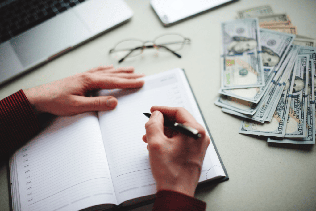Woman writing in journal with money on table