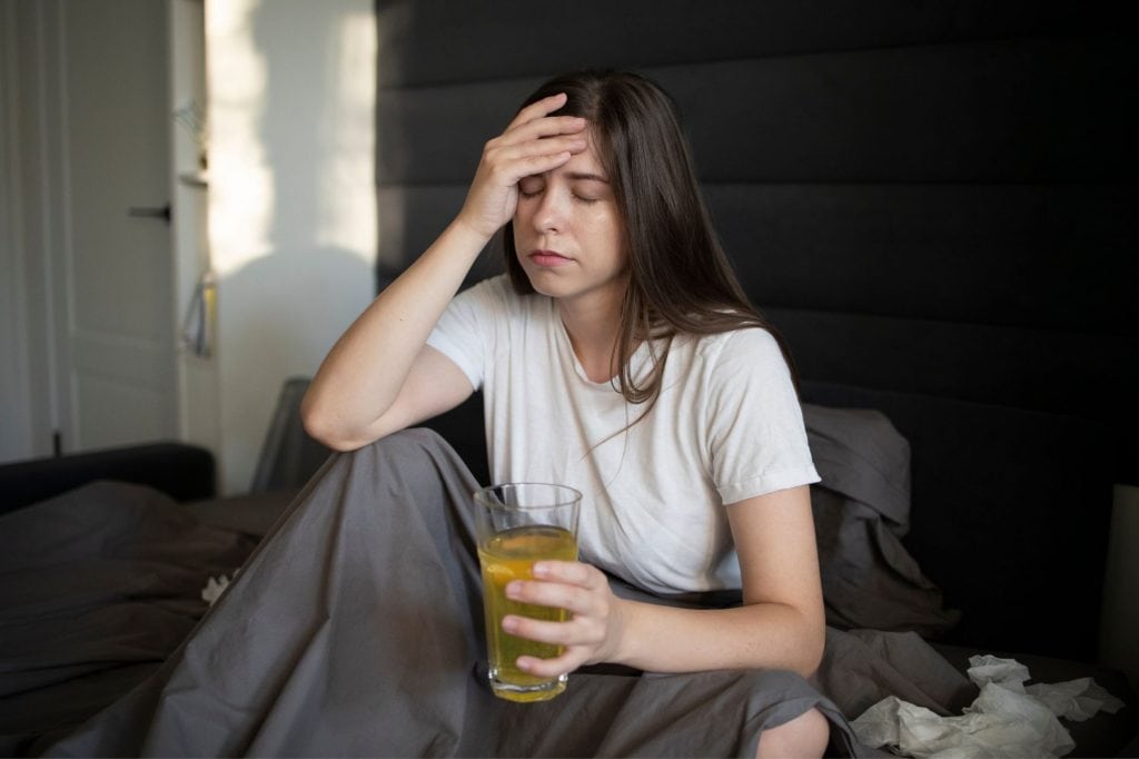 woman holding her forehead in bed