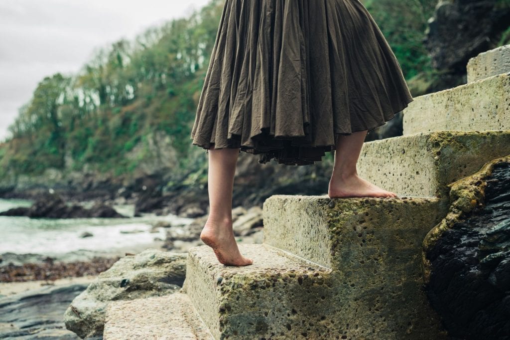 close up of woman's feet walking up stairs outside by water