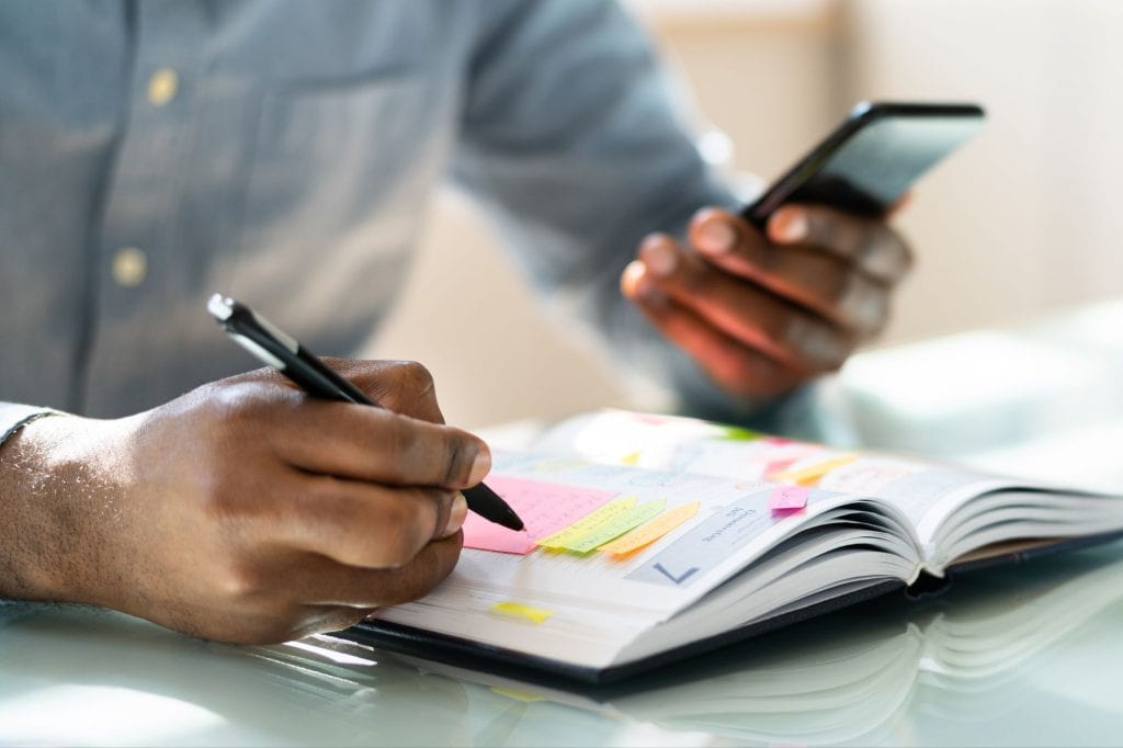 close up of man's hands writing in a planner
